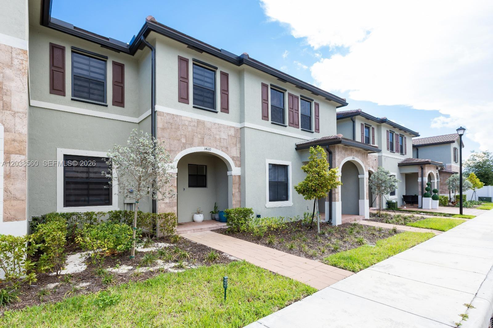 A row of two-story townhouses with stucco siding, stone accents, and brown shutters — 3420 W 111th Pl, Hialeah FL 33018, HIALEAH, FL