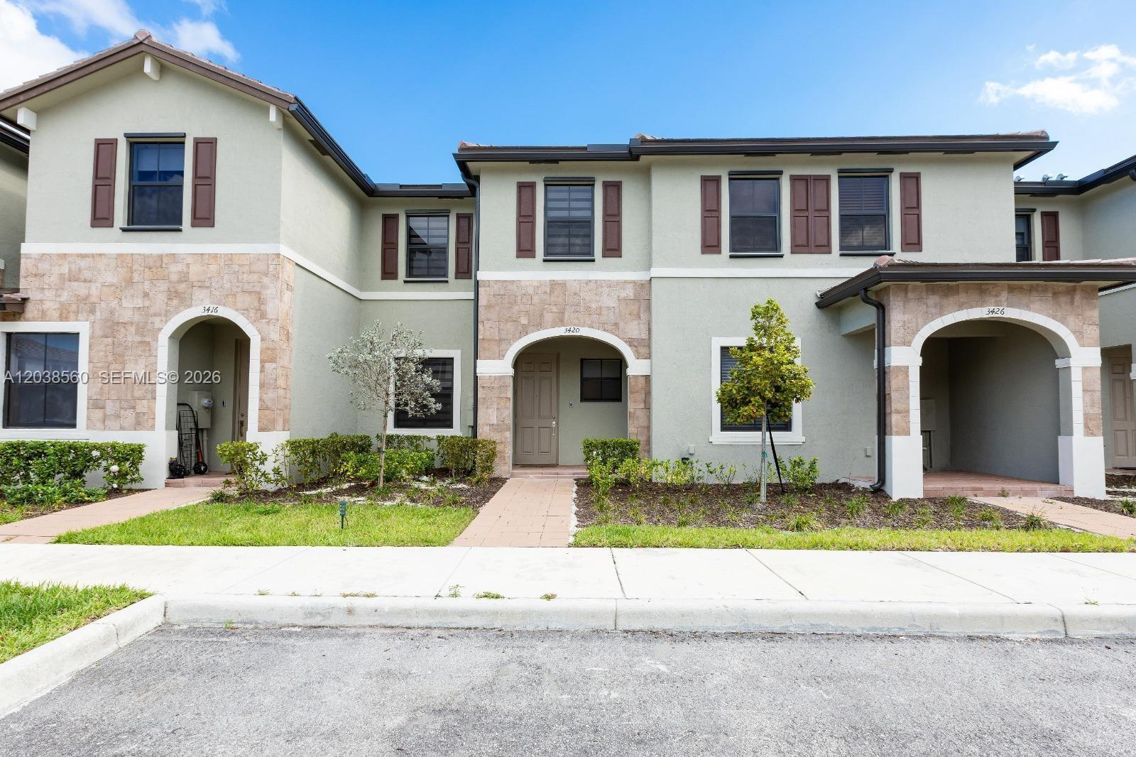 A row of two-story townhomes features light green stucco, stone accents, and brown shutters — 3420 W 111th Pl, Hialeah FL 33018, HIALEAH, FL