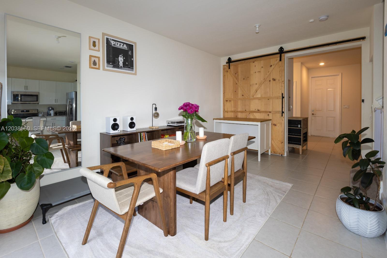 A dining room features a wooden table, four chairs, a sliding barn door, and tile flooring — 3420 W 111th Pl, Hialeah FL 33018, HIALEAH, FL