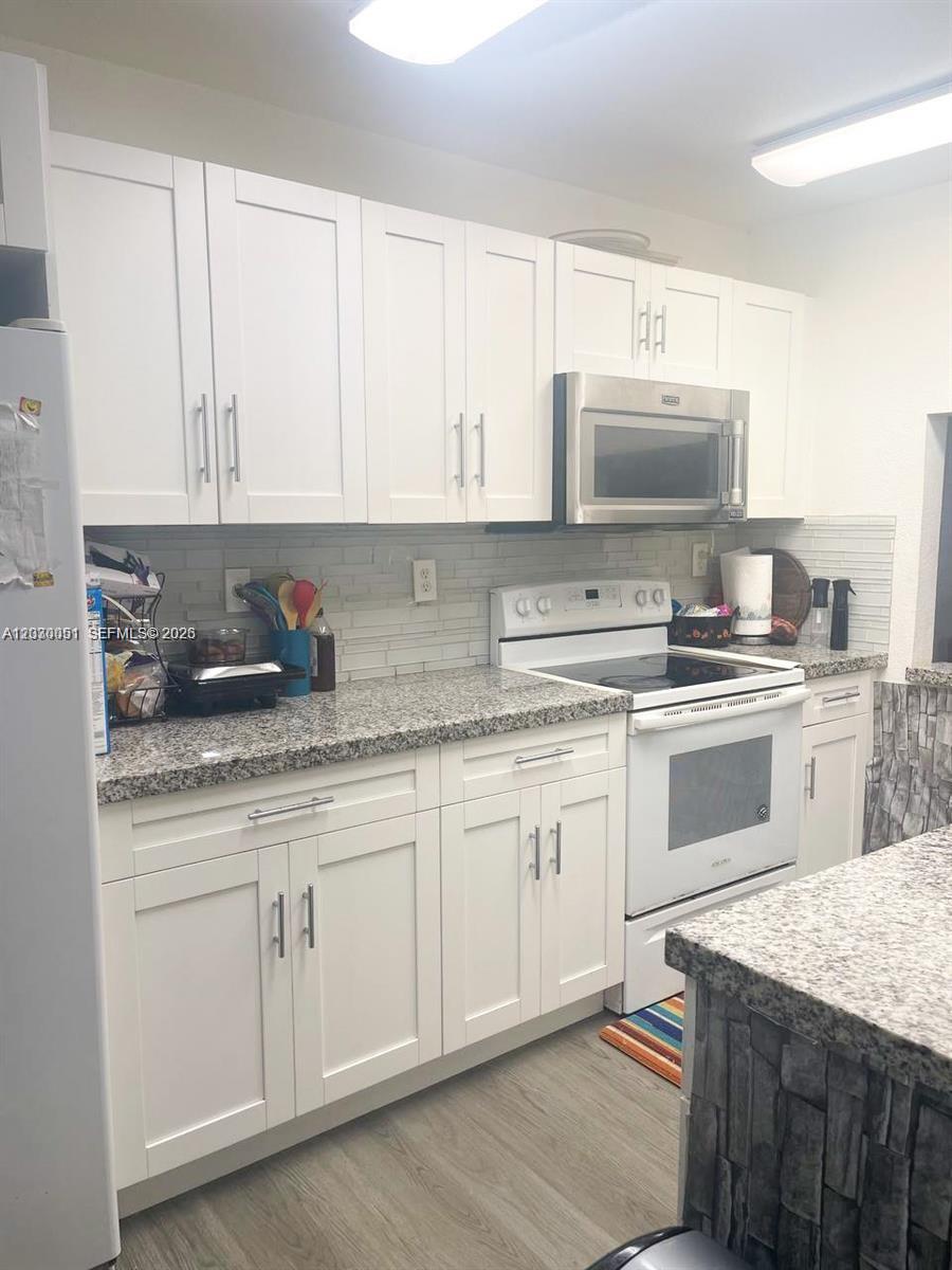 A kitchen features white shaker cabinets, granite countertops, a tiled backsplash, and stainless steel appliances — 177 Lakeview Dr # 104, Weston FL 33326, WESTON, FL