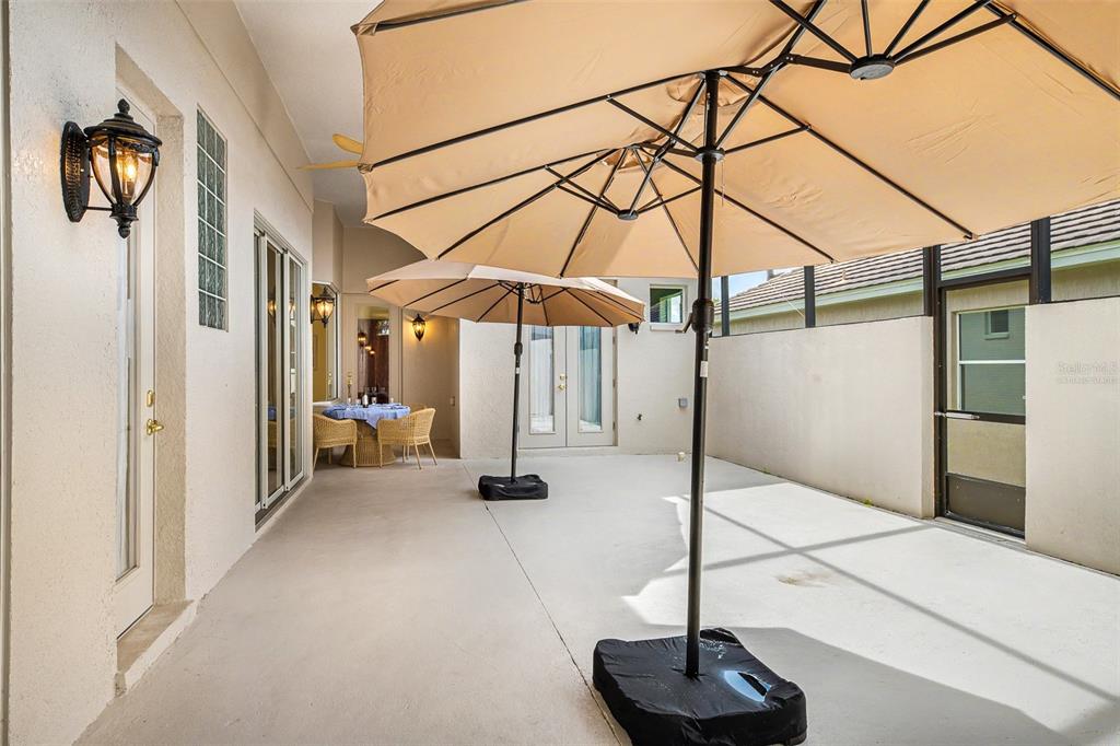 A concrete patio features two large tan umbrellas and a small dining set — 522 NEWHALL LANE, DEBARY, FL
