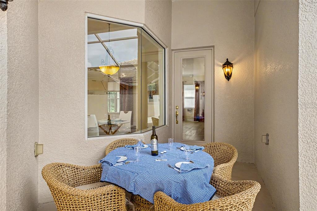 A covered patio features a round table with a blue checkered cloth and wicker chairs — 522 NEWHALL LANE, DEBARY, FL