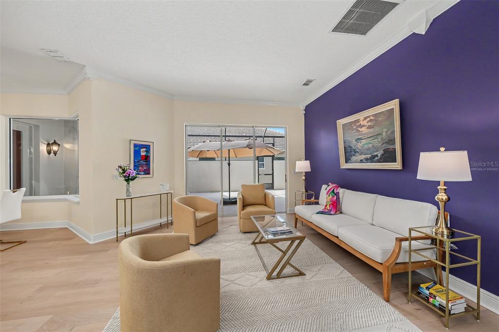 A living room features a purple accent wall, beige armchairs, a white sofa, and patio access — 522 NEWHALL LANE, DEBARY, FL