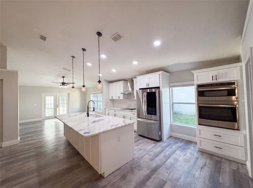 A modern kitchen features a marble-topped island, stainless steel appliances, and light wood-look flooring — 106 CABRILLO DRIVE, GROVELAND, FL