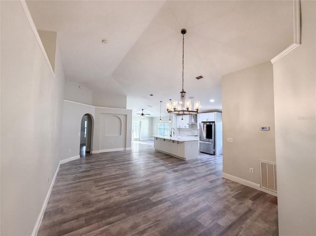 An open-concept living area features wood-look flooring, a kitchen island, and a chandelier — 106 CABRILLO DRIVE, GROVELAND, FL