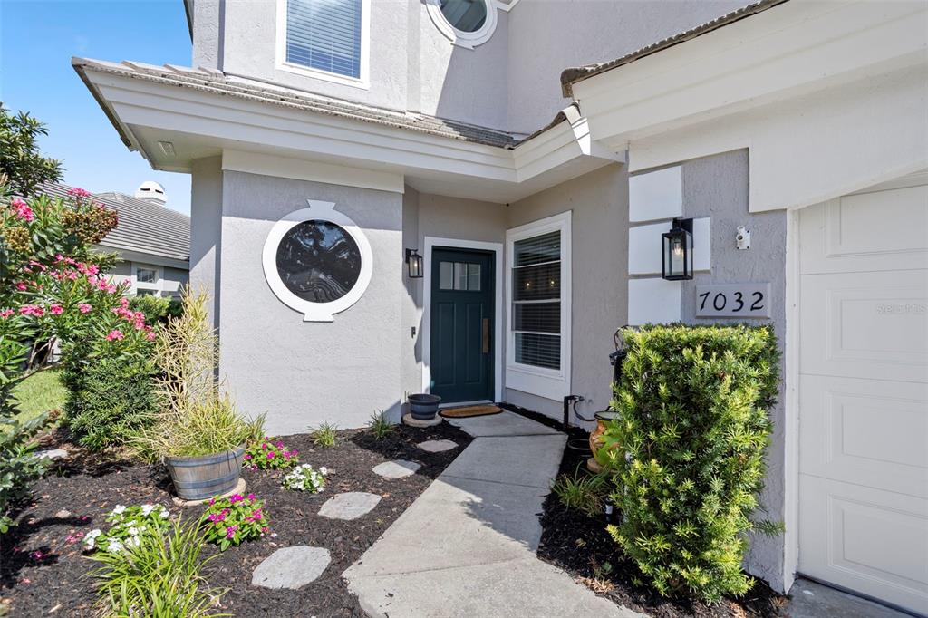 A gray house exterior features a dark front door, a circular window, and a walkway — 7032 SOMERTON BOULEVARD UNIT 54, ORLANDO, FL