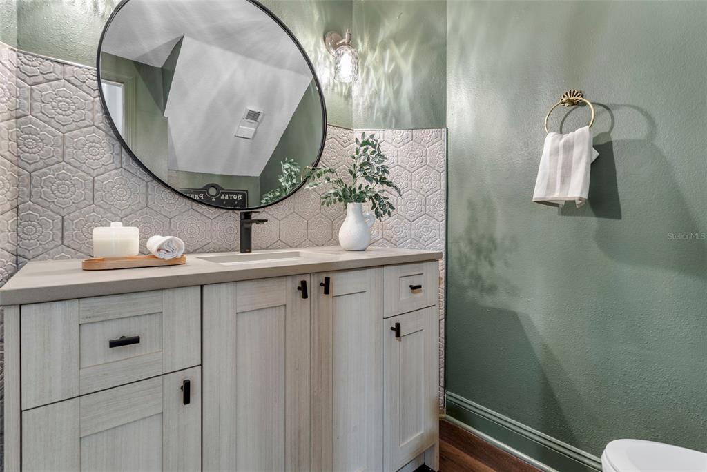 A bathroom features a light wood vanity, a round mirror, and sage green walls — 7032 SOMERTON BOULEVARD UNIT 54, ORLANDO, FL