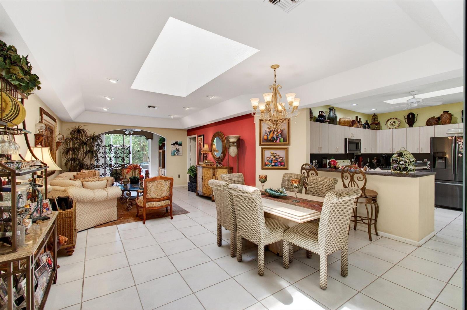 An open-concept living and dining area features tile floors, a skylight, and a kitchen island — 12527 Crystal Pointe Drive # C, Boynton Beach FL 33437, BOYNTON BEACH, FL
