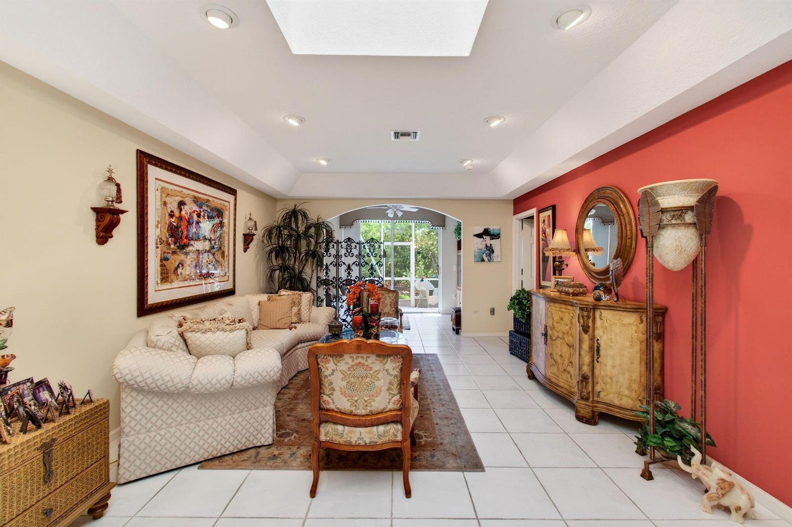 A living room features a tray ceiling, white tile floors, and a red accent wall — 12527 Crystal Pointe Drive # C, Boynton Beach FL 33437, BOYNTON BEACH, FL