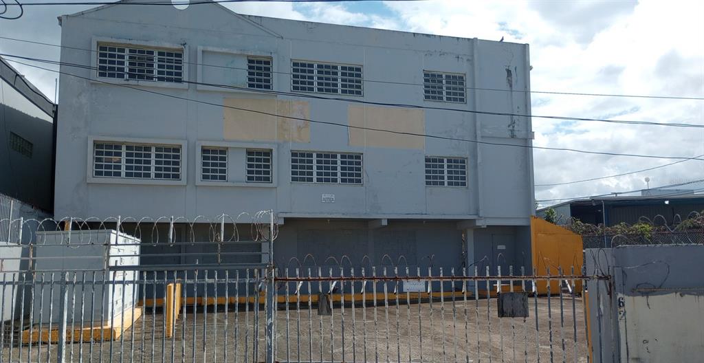 A three-story gray commercial building sits behind a metal fence topped with barbed wire — 662 DE DIEGO AVE SABANA LLANA WARD AVENUE, SAN JUAN, PR