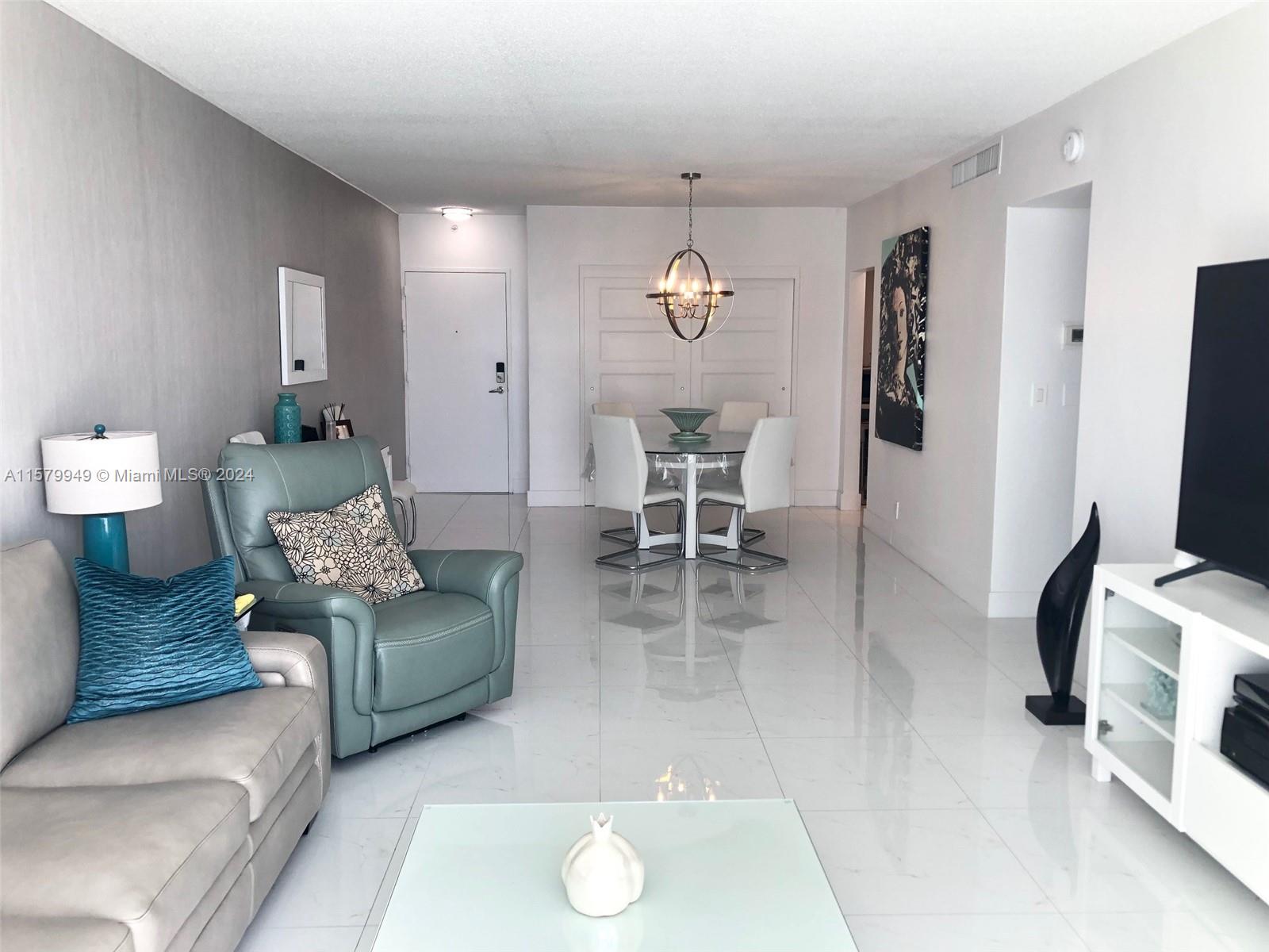 A living and dining area features white tile floors, a glass table, and modern furniture — 3901 S Ocean Dr # 14M, Hollywood FL 33019, HOLLYWOOD, FL