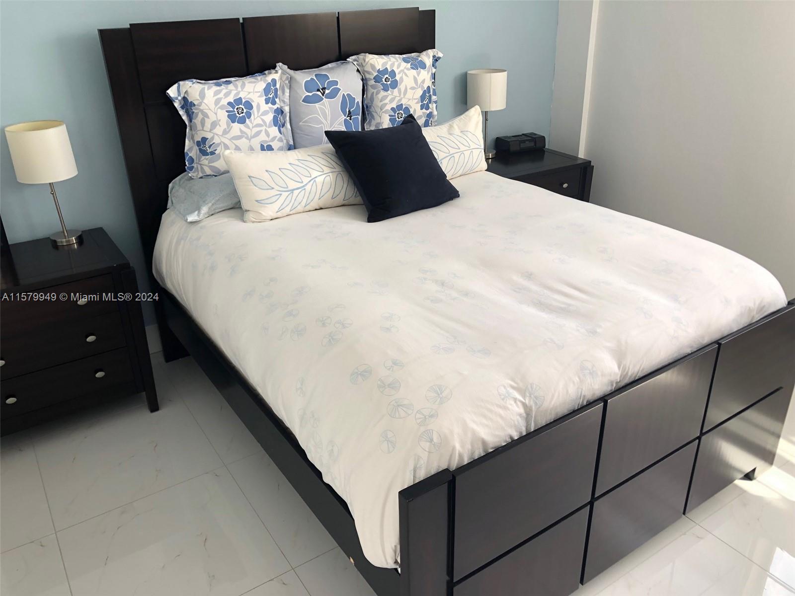 A bedroom features a dark wood bed frame, a white floral duvet, and matching nightstands — 3901 S Ocean Dr # 14M, Hollywood FL 33019, HOLLYWOOD, FL