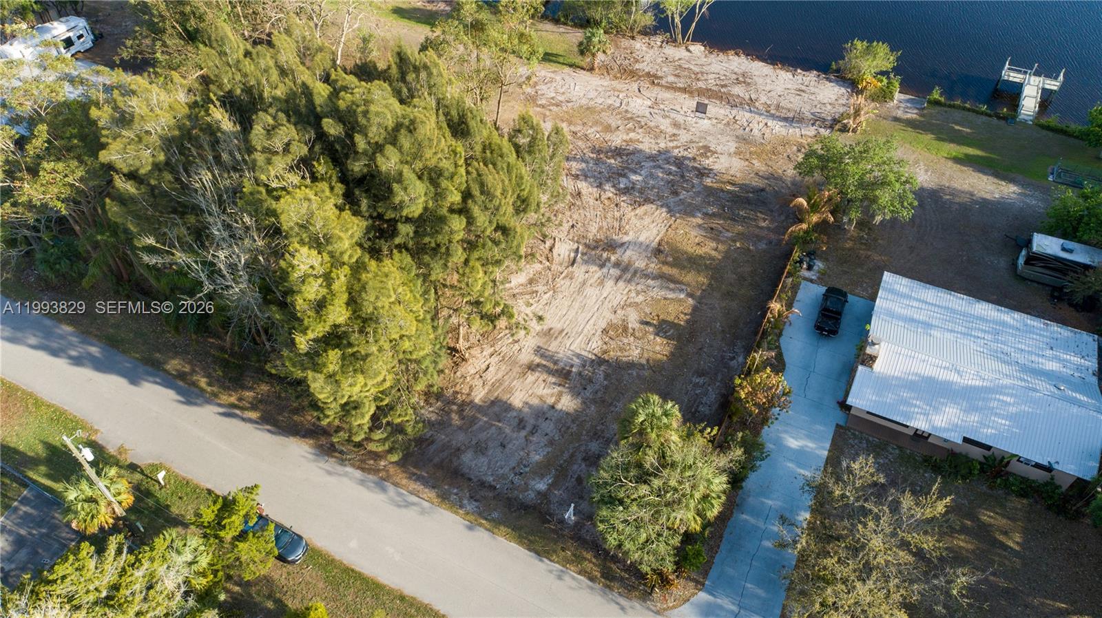 An aerial view shows a vacant, cleared lot situated between a road and a waterway — 1035 W Anchor Lane, Moore Haven FL 33471, MOORE HAVEN, FL