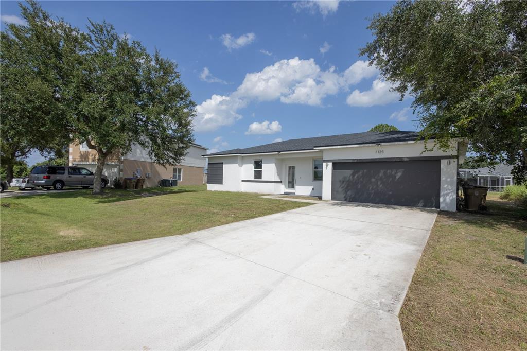 A single-story house with a white exterior, dark roof, and a two-car garage — 1125 MUNSTER COURT, KISSIMMEE, FL