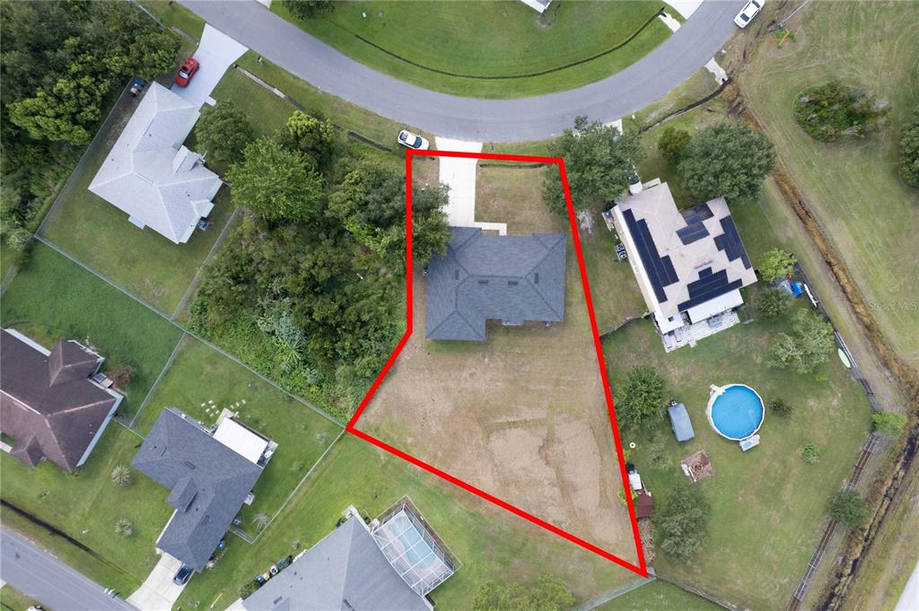 An aerial view shows a house with a large, irregularly shaped backyard outlined in red — 1125 MUNSTER COURT, KISSIMMEE, FL