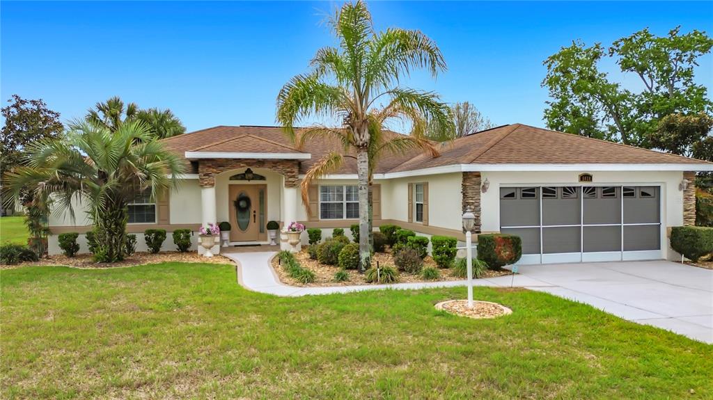 A single-story house with a tan exterior, stone accents, a palm tree, and a garage — 5028 NW 34TH PLACE, OCALA, FL