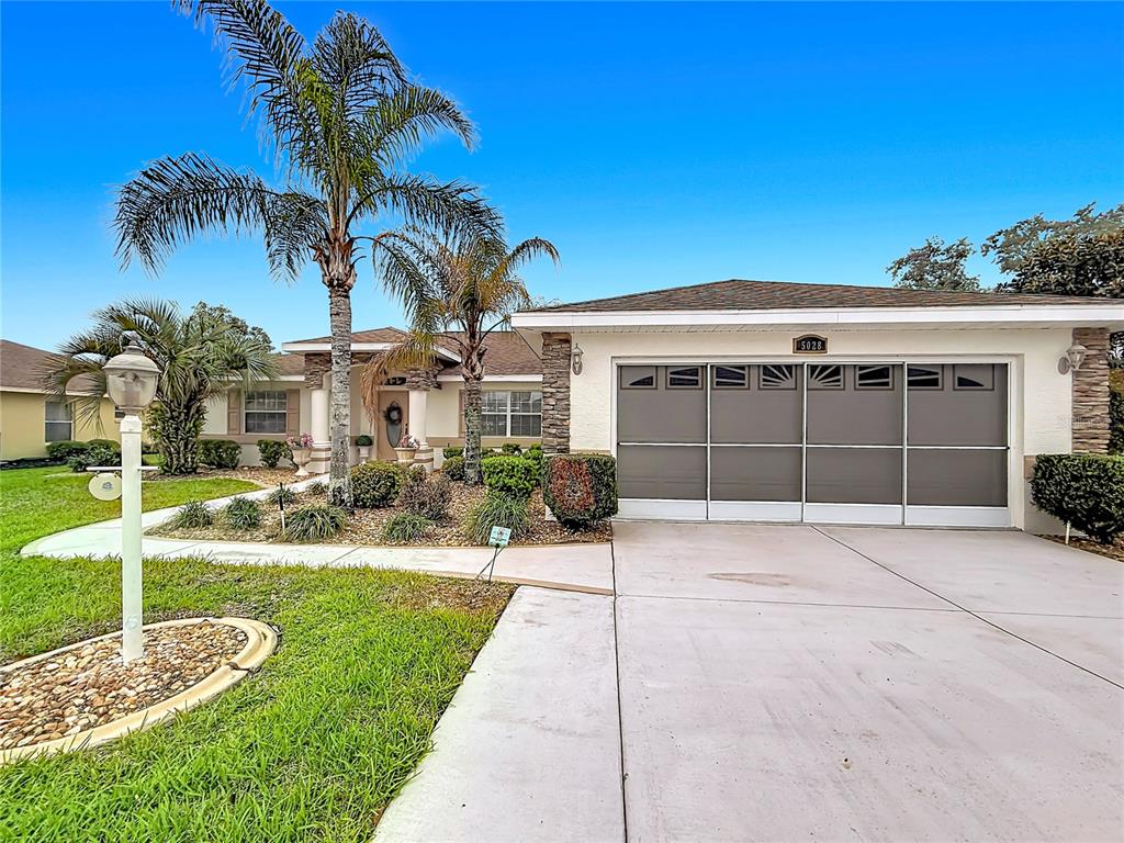 A single-story house features a concrete driveway, a multi-panel garage door, and palm trees — 5028 NW 34TH PLACE, OCALA, FL