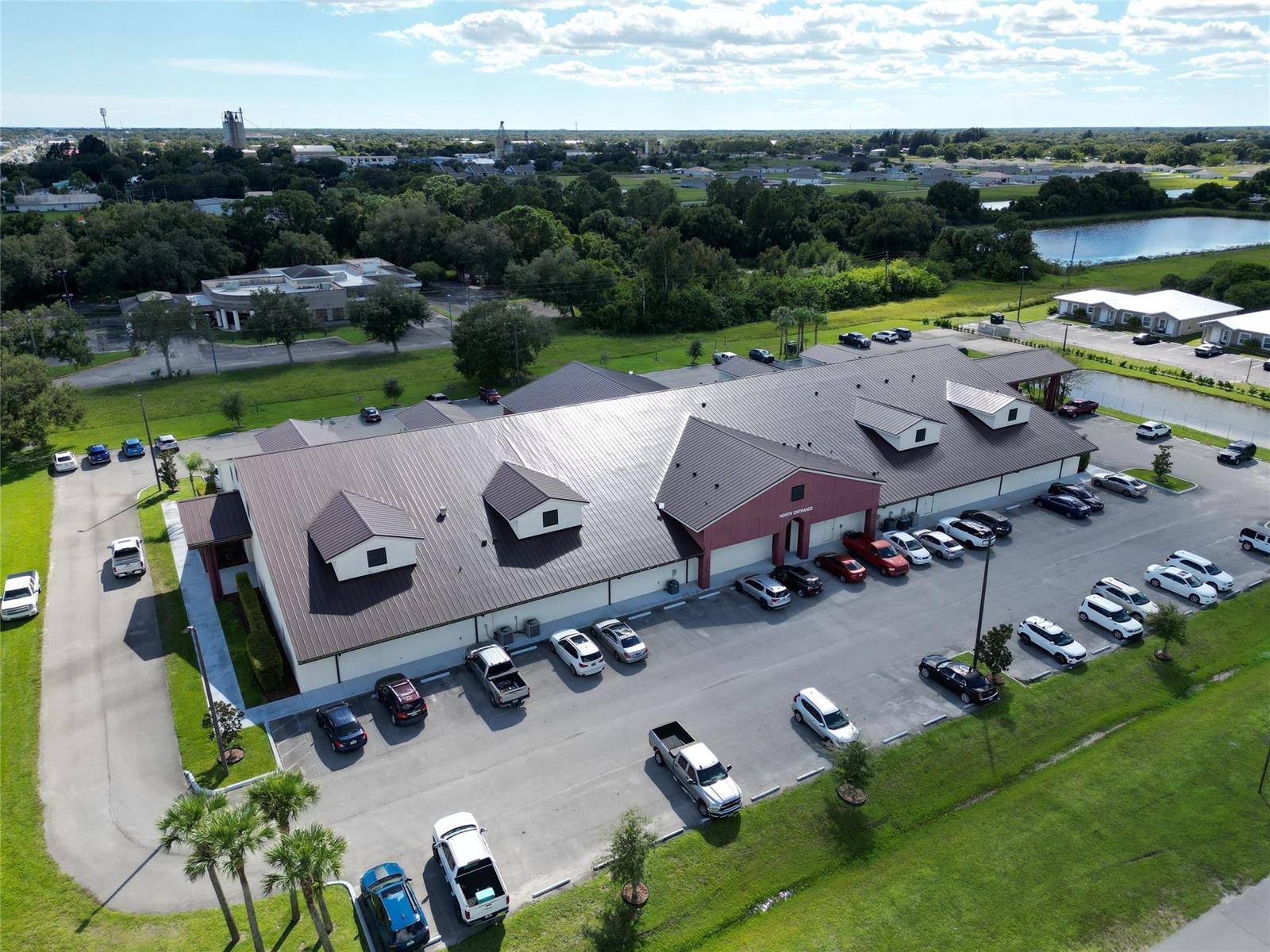An aerial view shows a commercial building with a metal roof and a parking lot — 1713 US Highway 441 # F, Okeechobee FL 34972, OKEECHOBEE, FL