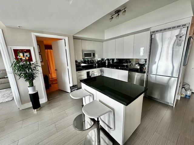 A modern kitchen features white cabinetry, a black island with bar stools, and stainless appliances — 92 SW 3rd St # 4104, Miami FL 33130, MIAMI, FL