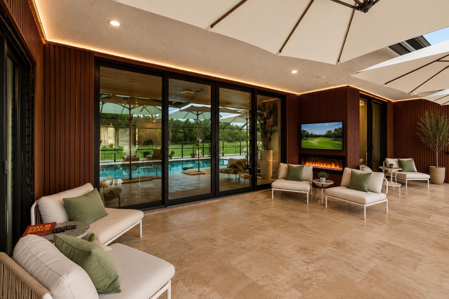 A covered outdoor patio features wood-slat walls, a fireplace, a television, and views of a pool — 10710 Boca Woods Lane, Boca Raton FL 33428, BOCA RATON, FL