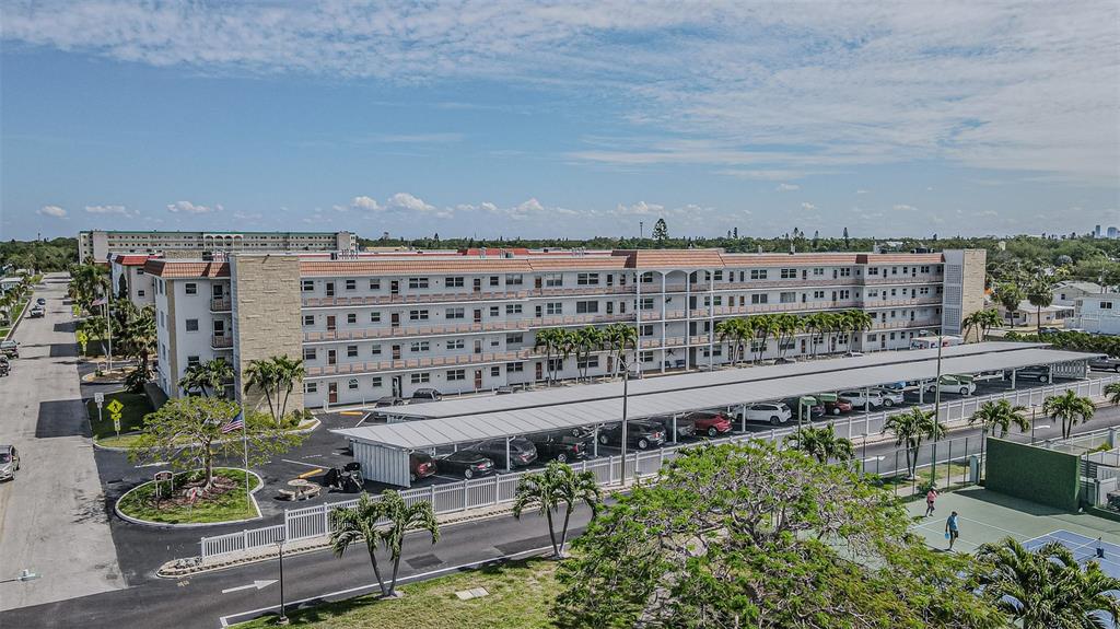 An aerial view of a multi-story apartment building with a covered parking lot and tennis court — 3128 59TH STREET S UNIT 110, GULFPORT, FL