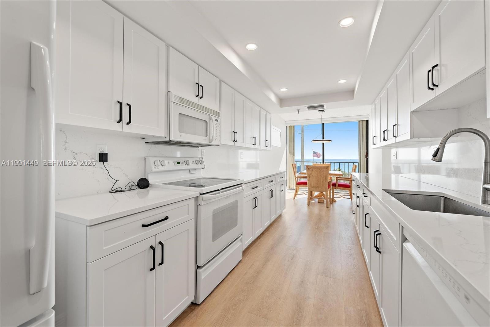 A galley kitchen features white cabinets, quartz countertops, and a view of the ocean — 1300 S Highway A1a # 402, Jupiter FL 33477, JUPITER, FL