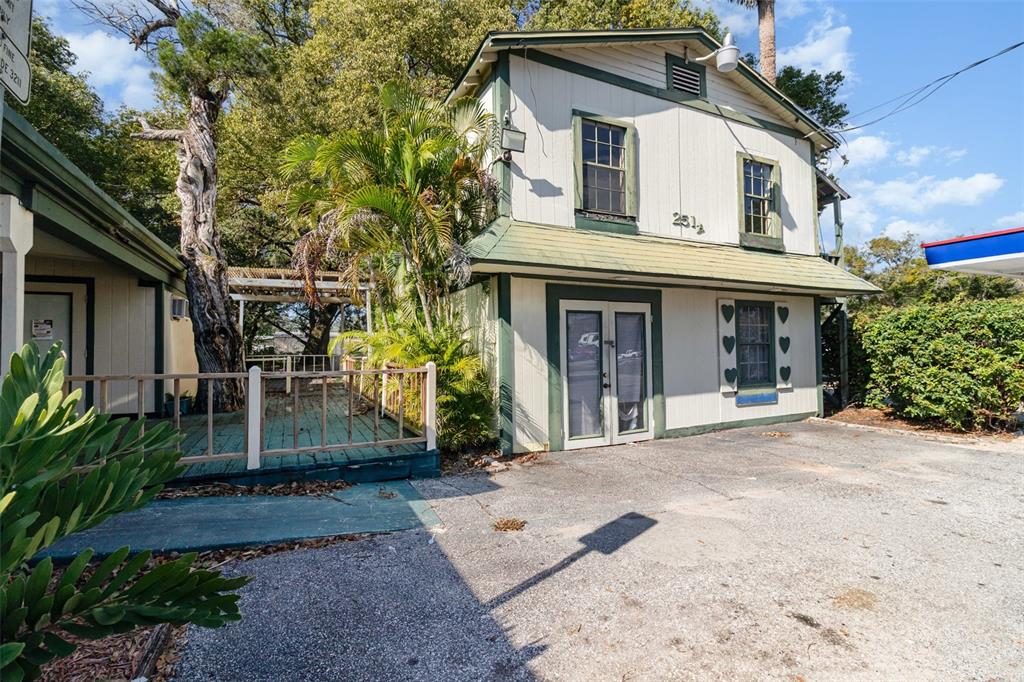 A two-story building with white siding, green trim, and a wooden deck stands outdoors — 2516 SANFORD AVENUE, SANFORD, FL