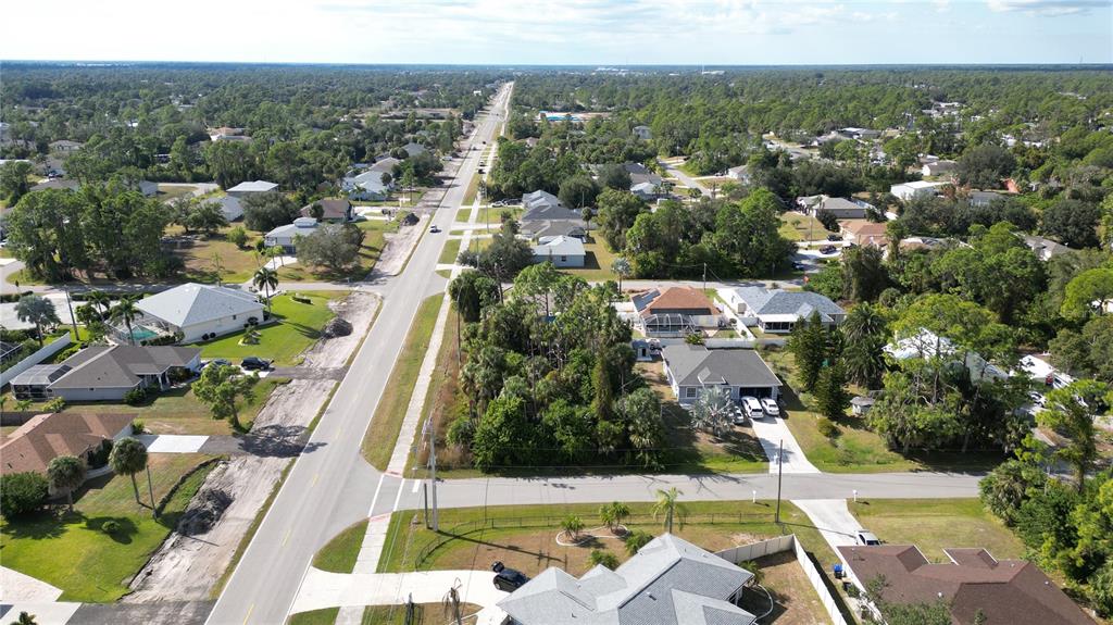 An aerial view shows a suburban neighborhood with houses, green trees, and a paved road — 0 W PRICE BOULEVARD, NORTH PORT, FL