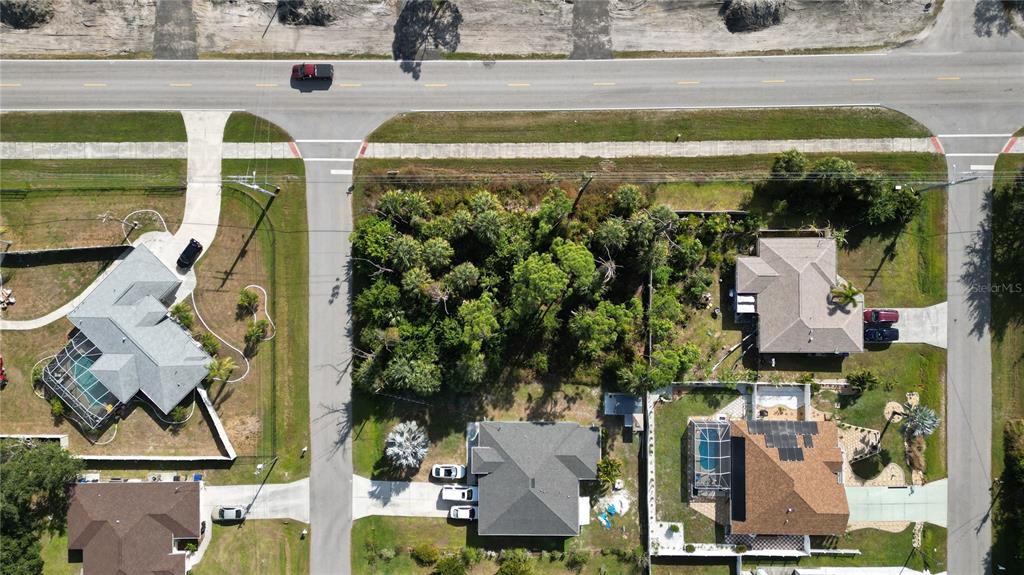 An aerial view shows a vacant, wooded residential lot situated between two houses — 0 W PRICE BOULEVARD, NORTH PORT, FL