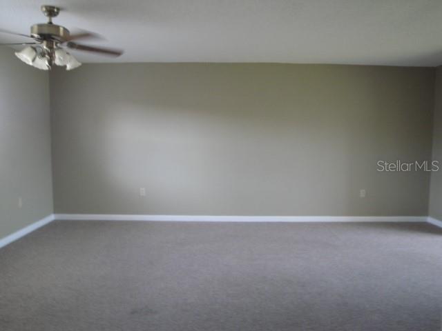 An empty room with beige walls, carpeted flooring, and a ceiling fan — 7701 STARKEY ROAD UNIT 622, SEMINOLE, FL