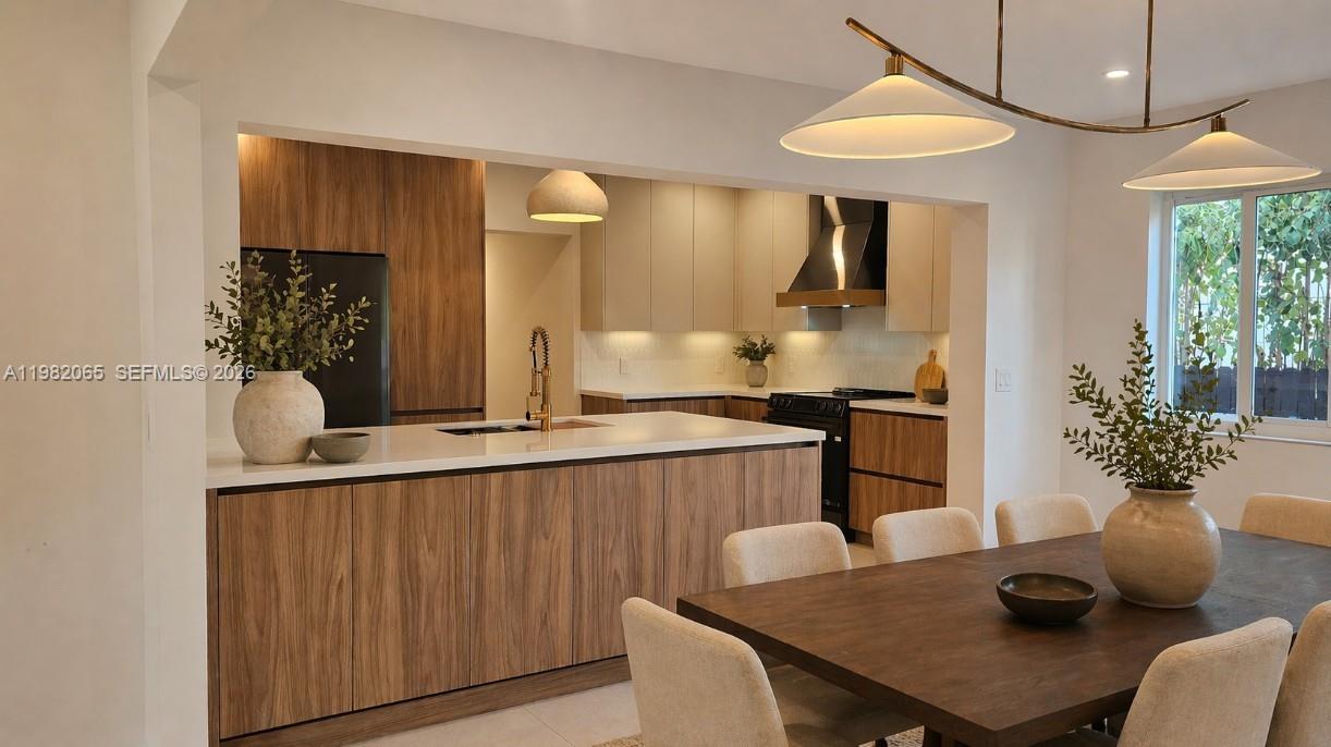 A modern kitchen features wood-grain cabinetry, a white island countertop, and an adjacent dining area — 2365 SW 21st Ave, Miami FL 33145, MIAMI, FL