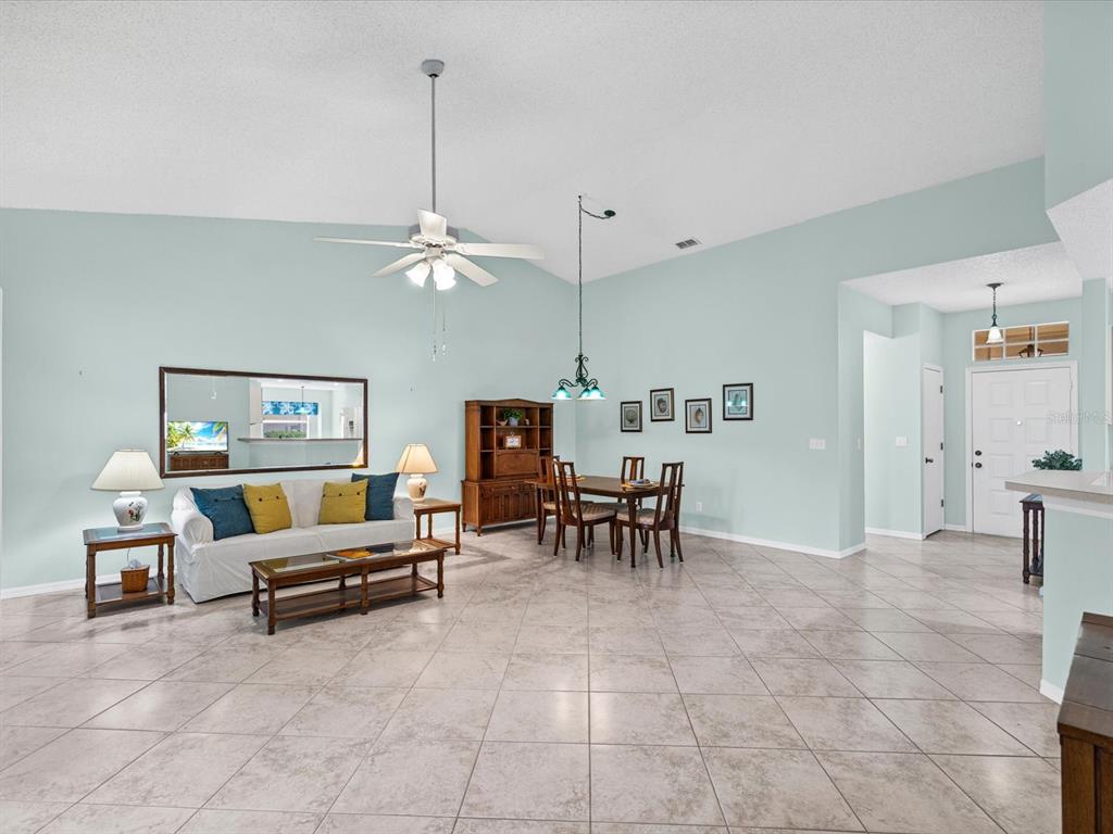 A spacious living and dining area features light blue walls, tile flooring, and vaulted ceilings — 830 MCCALLISTER AVENUE, SUN CITY CENTER, FL