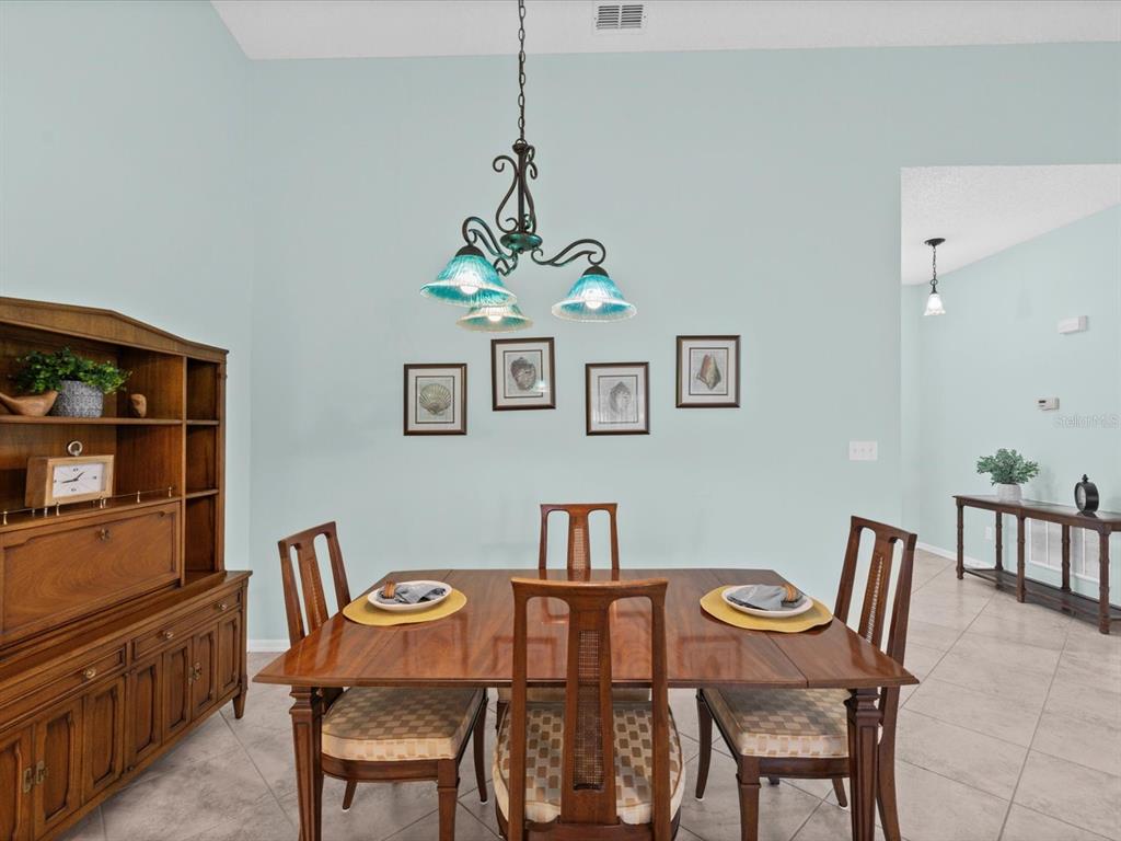 A dining room features a wooden table, chairs, a hutch, and a hanging light fixture — 830 MCCALLISTER AVENUE, SUN CITY CENTER, FL