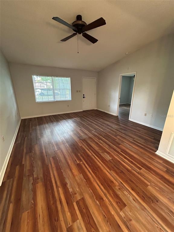 An empty living room features wood-look flooring, a ceiling fan, and a white front door — 955 N SUNSET DRIVE, MOUNT DORA, FL