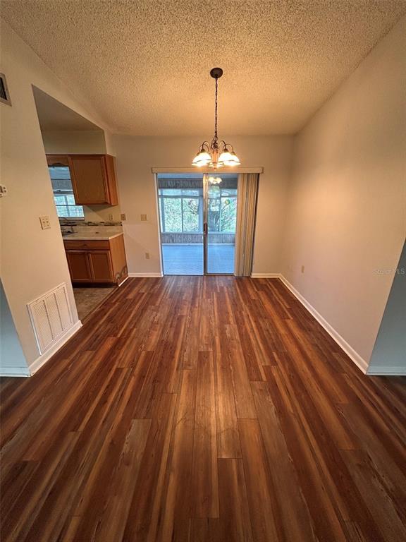 A dining area with wood-look flooring, a hanging light fixture, and a sliding glass door — 955 N SUNSET DRIVE, MOUNT DORA, FL