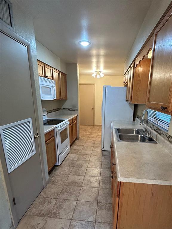 A galley kitchen features oak cabinets, laminate countertops, a white stove, and tile flooring — 955 N SUNSET DRIVE, MOUNT DORA, FL