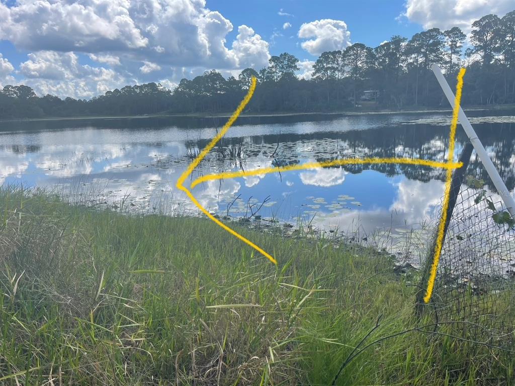 A view of a lake from a grassy shoreline with a fence post in the foreground — 42318 W LAKE ROAD, DELAND, FL
