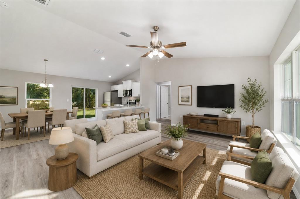 An open-concept living and dining area features light wood flooring, a vaulted ceiling, and kitchen — 44 ALMOND ROAD, OCALA, FL