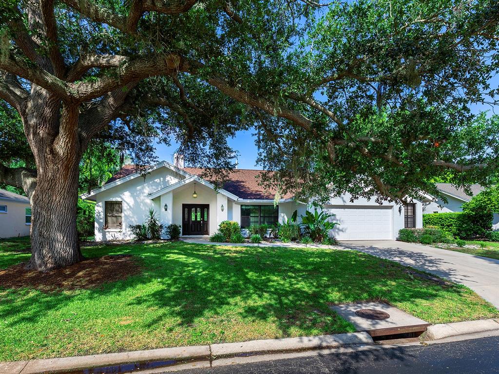 A white single-story house with a two-car garage sits behind a large oak tree — 1756 COTTONWOOD TRAIL, SARASOTA, FL