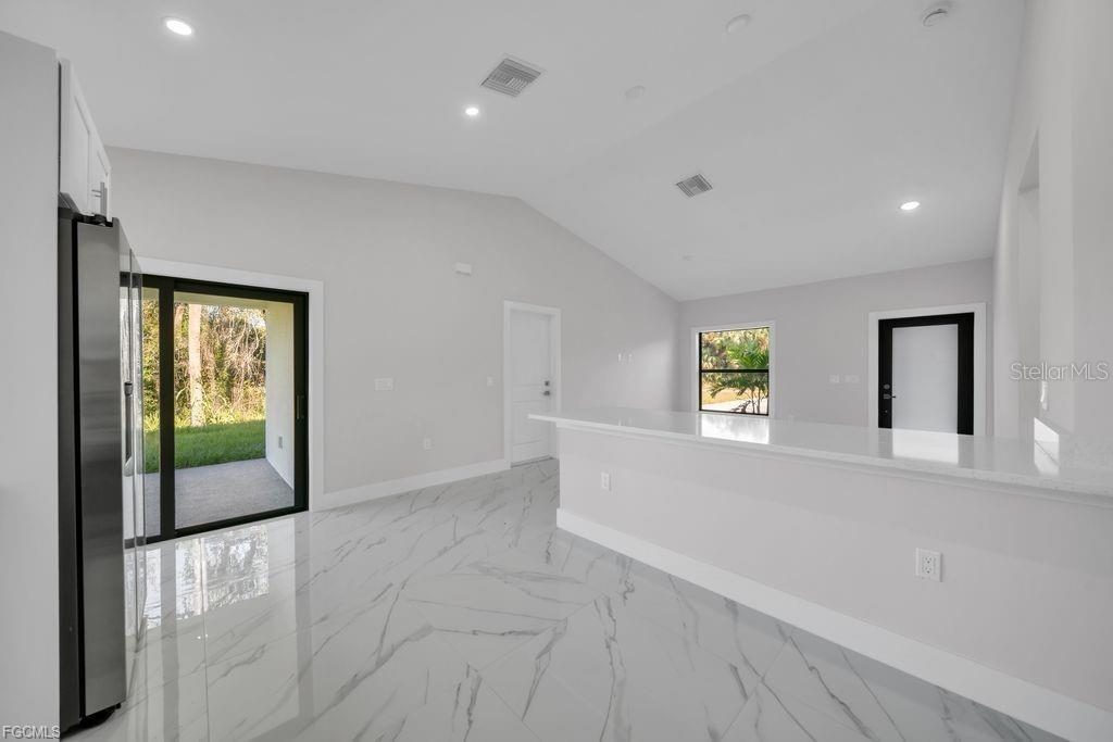 A bright kitchen features white cabinets, a quartz breakfast bar, and polished marble-look tile flooring — 644 WOODCREST DR, LEHIGH ACRES, FL