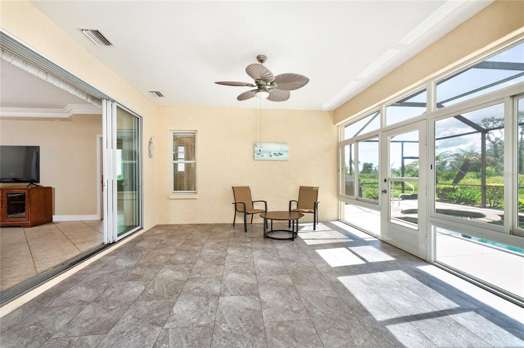 A sunroom with tile flooring, a ceiling fan, and sliding glass doors leading to a pool — 682 BARNACLE COURT, ENGLEWOOD, FL