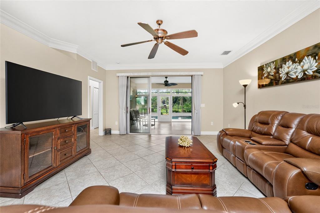 A living room features a brown leather sofa, wooden media console, and sliding glass doors — 682 BARNACLE COURT, ENGLEWOOD, FL
