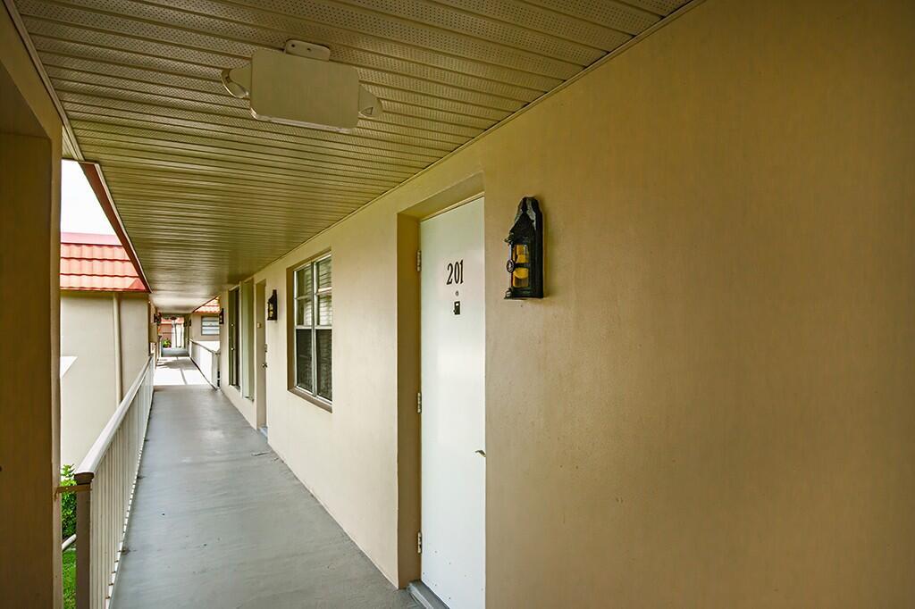 An exterior apartment hallway features a white door labeled 201, a wall-mounted lantern, and railings — VERO BEACH, FL