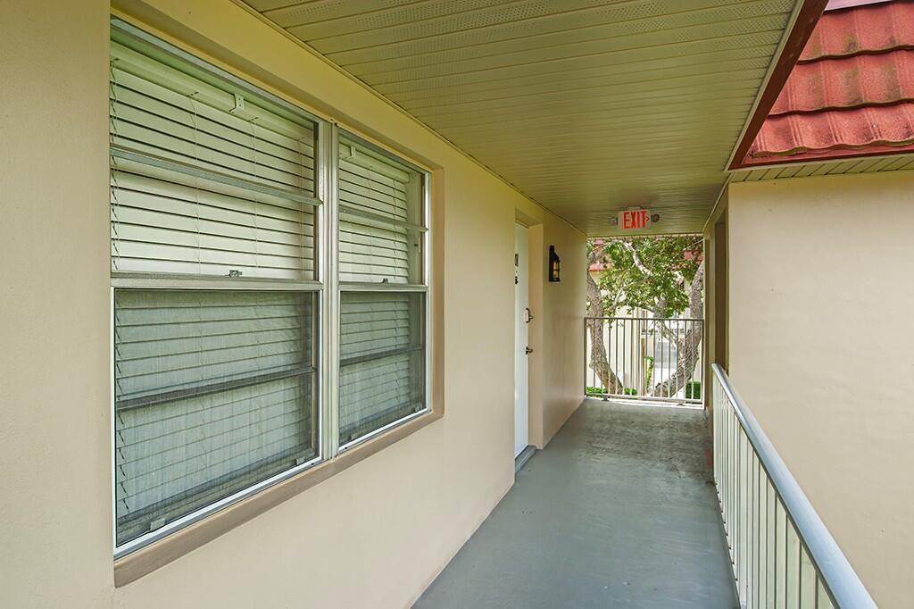 An outdoor walkway with a metal railing leads to a building entrance with windows — VERO BEACH, FL