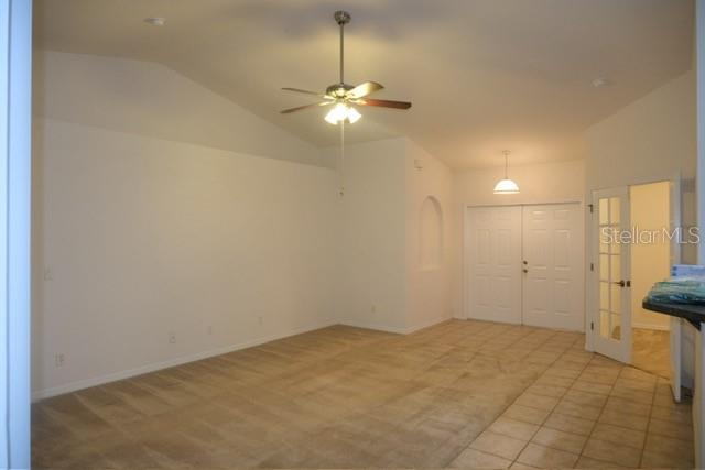 An interior room features a vaulted ceiling, a ceiling fan, carpet, and tile flooring — 1430 SEAPORT STREET, NORTH PORT, FL