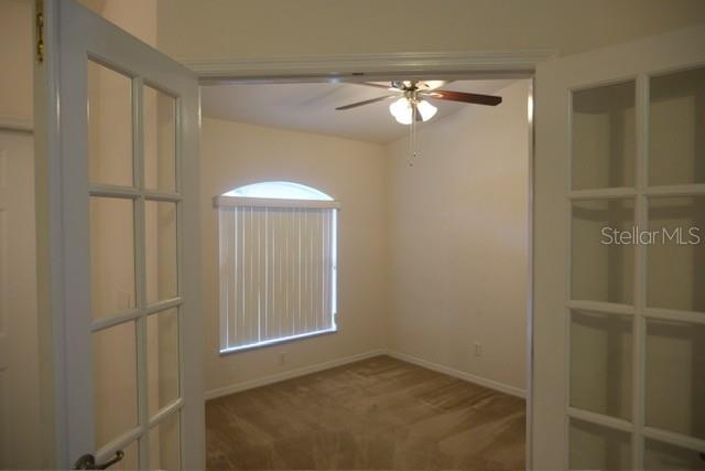 A view through French doors into a carpeted room with a ceiling fan and arched window — 1430 SEAPORT STREET, NORTH PORT, FL