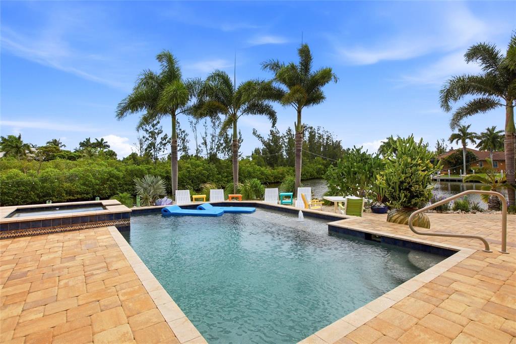 A swimming pool and spa on a paved patio overlooking a canal and palm trees — 3506 MARSALA COURT, PUNTA GORDA, FL