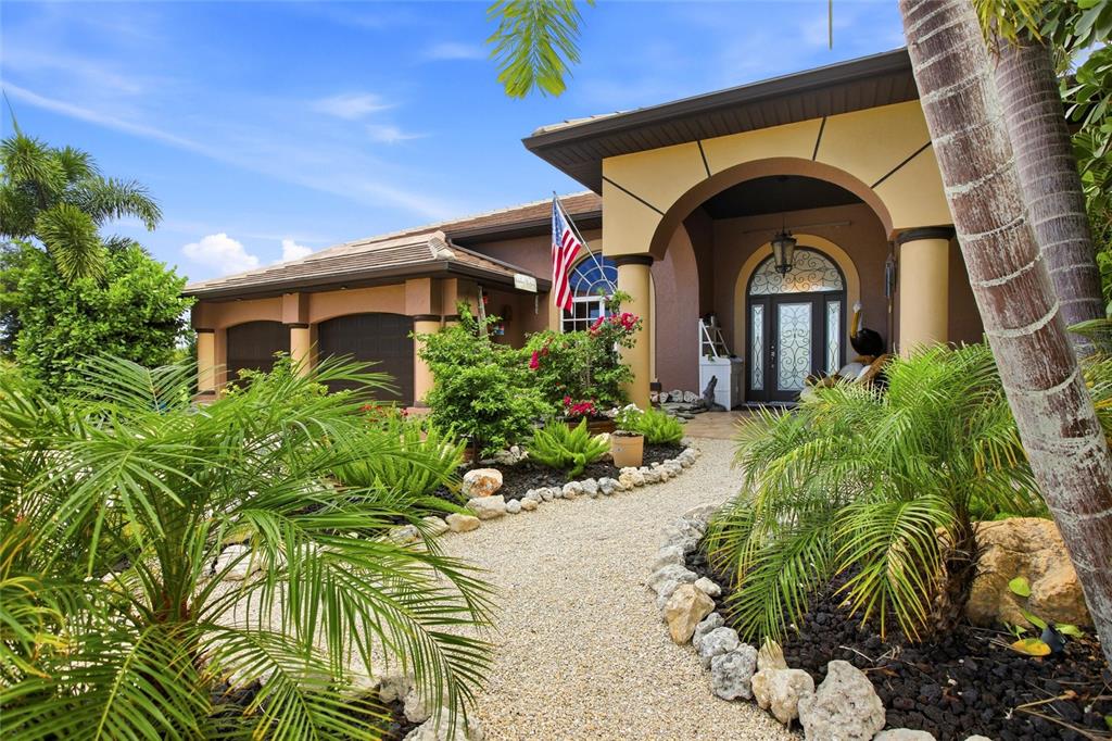 A gravel path leads to the arched entryway of a house with palm trees — 3506 MARSALA COURT, PUNTA GORDA, FL