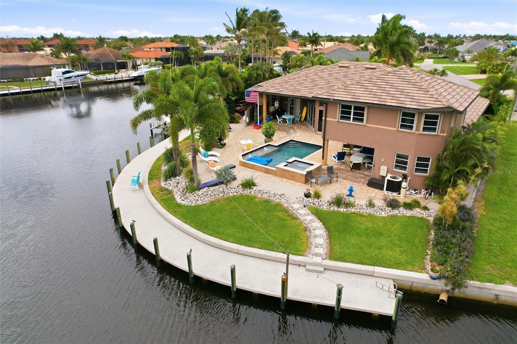 An aerial view shows a waterfront house with a pool, patio, and private dock — 3506 MARSALA COURT, PUNTA GORDA, FL