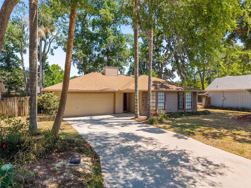 A single-story house with a tan exterior, a two-car garage, and a concrete driveway — 4363 NW 61ST TERRACE, GAINESVILLE, FL